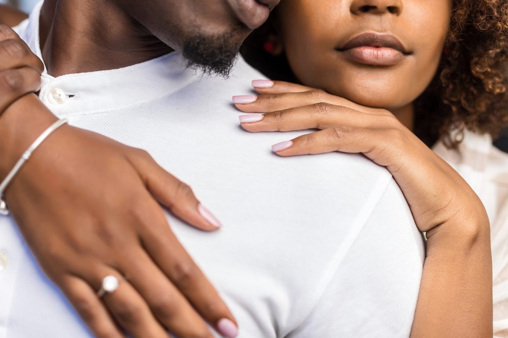 A husband and wife embracing, her hand resting on his shoulder