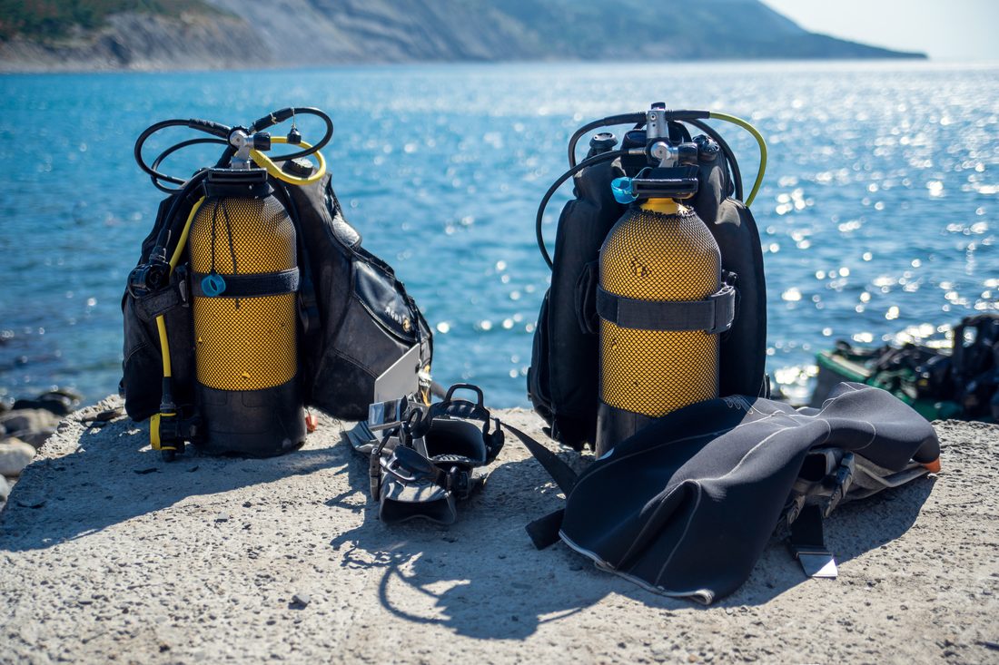 Scuba diving gear resting on the sand by the water